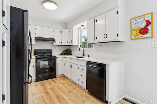 kitchen with under cabinet range hood, light countertops, white cabinets, black appliances, and a sink