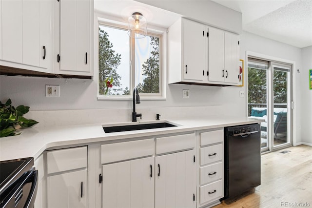 kitchen featuring a sink, black appliances, light countertops, and white cabinetry