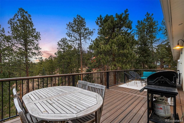 wooden deck with outdoor dining space and area for grilling