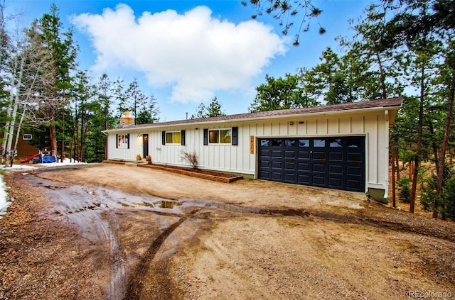 single story home featuring board and batten siding, a chimney, and driveway