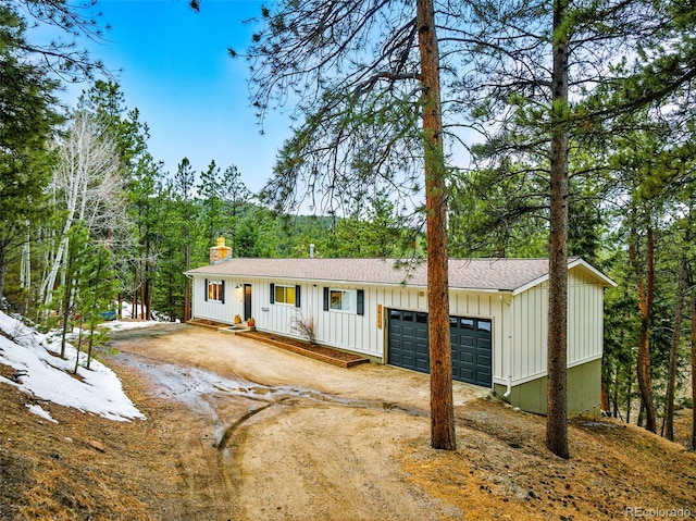 view of front of house with a garage, driveway, board and batten siding, and a chimney