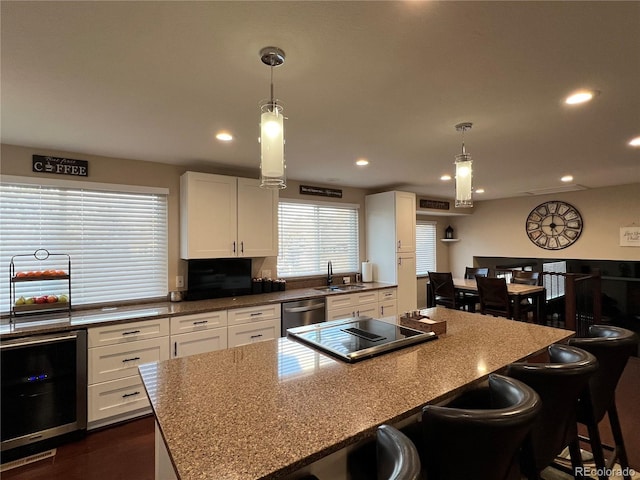 kitchen with sink, white cabinetry, a kitchen bar, hanging light fixtures, and wine cooler