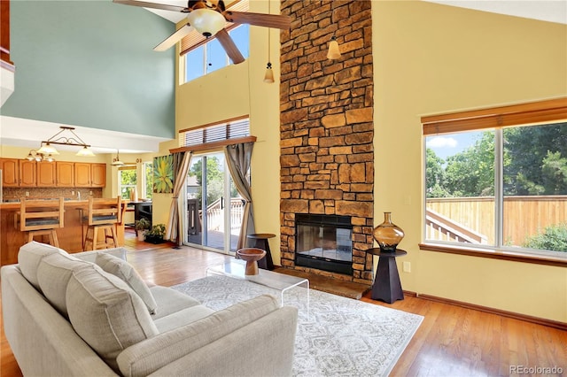 9682 Hemlock Ct, Highlands Ranch, CO 80130 - living room with a towering ceiling, ceiling fan, plenty of natural light, light wood-style floors, and a fireplace