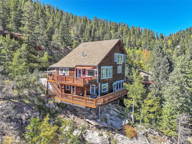 31324 Kings Vly, Conifer, CO 80433 - rear view of property featuring a forest view, a wooden deck, and a shingled roof