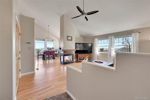 31324 Kings Vly, Conifer, CO 80433 - living room featuring a ceiling fan, light wood-style floors, a multi sided fireplace, baseboards, and high vaulted ceiling