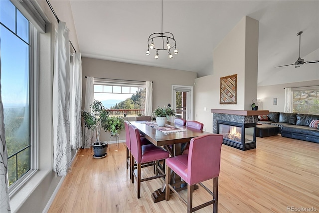 31324 Kings Vly, Conifer, CO 80433 - dining space featuring light wood-style floors, a multi sided fireplace, a chandelier, baseboards, and a ceiling fan
