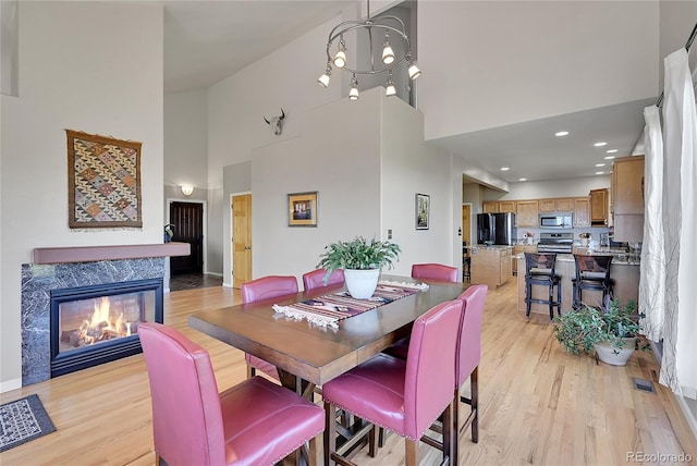 31324 Kings Vly, Conifer, CO 80433 - dining room with a high ceiling, light wood-style floors, a premium fireplace, and baseboards