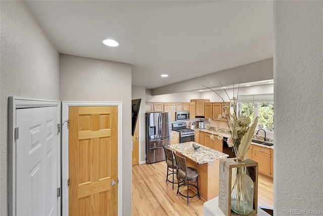 31324 Kings Vly, Conifer, CO 80433 - kitchen with appliances with stainless steel finishes, a textured wall, light wood finished floors, a center island, and a breakfast bar