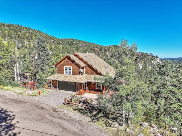 31324 Kings Vly, Conifer, CO 80433 - view of front of property with dirt driveway, a forest view, a garage, and a mountain view