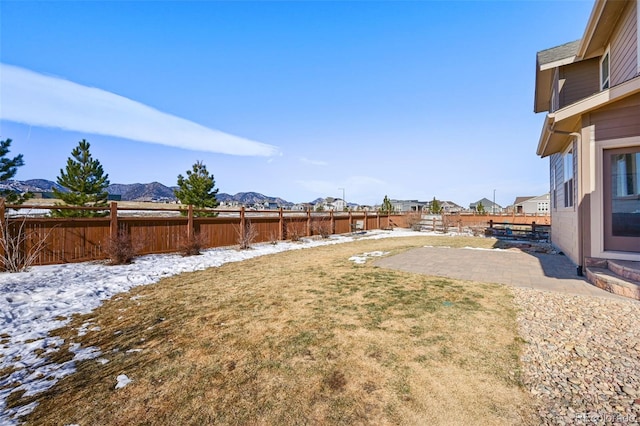 yard covered in snow featuring a mountain view and a patio area