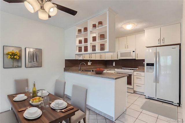 kitchen featuring decorative backsplash, sink, white appliances, and kitchen peninsula