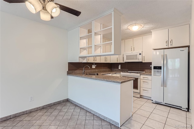 kitchen featuring kitchen peninsula, backsplash, white appliances, ceiling fan, and sink