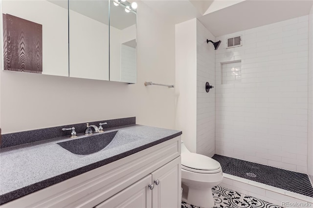 bathroom featuring tiled shower, tile patterned floors, vanity, and toilet