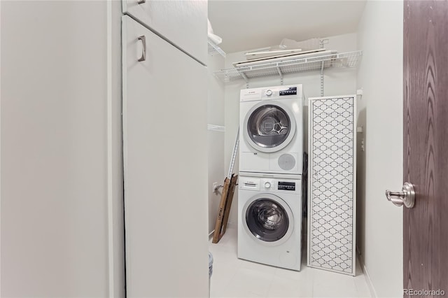 laundry room featuring stacked washing maching and dryer and light tile patterned floors