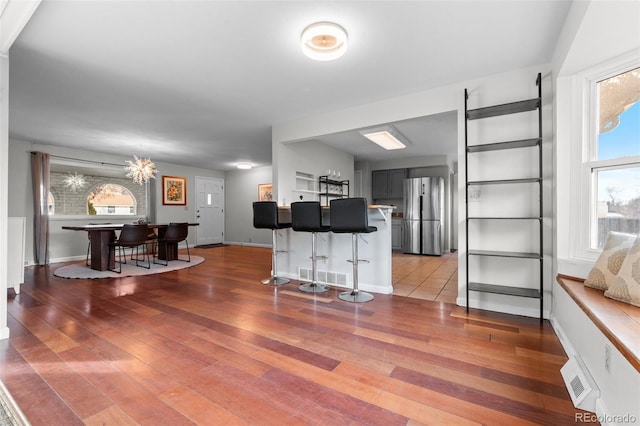 kitchen with hardwood / wood-style flooring, stainless steel fridge, and a breakfast bar