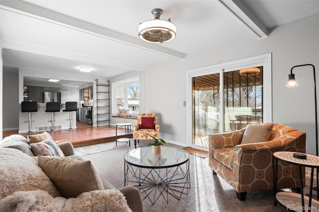 living room featuring beamed ceiling, a healthy amount of sunlight, and hardwood / wood-style floors