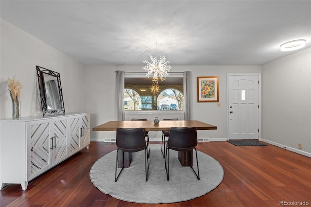 dining space with dark wood-type flooring and a notable chandelier