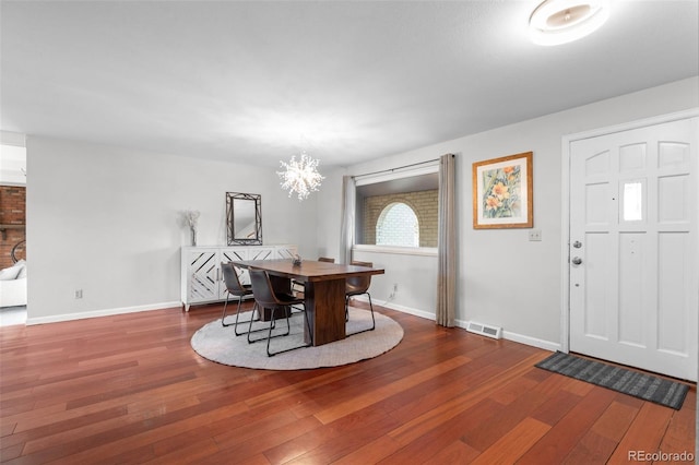 dining space with dark wood-type flooring and an inviting chandelier