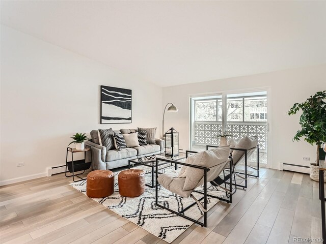 living room with baseboard heating and light hardwood / wood-style flooring