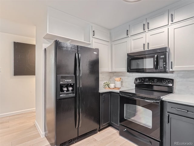 kitchen with light wood-type flooring, gray cabinets, backsplash, white cabinetry, and black appliances