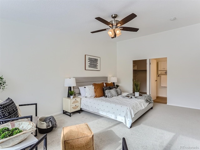 carpeted bedroom with ceiling fan, a spacious closet, and connected bathroom