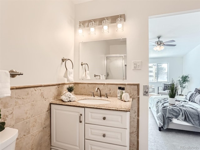 bathroom featuring tile walls, toilet, vanity, and ceiling fan