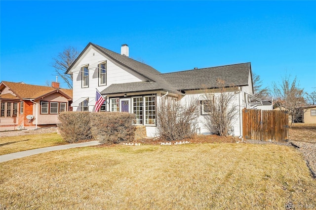 exterior space with a front lawn, roof with shingles, and fence