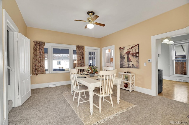 dining room featuring baseboards, visible vents, a ceiling fan, and light colored carpet