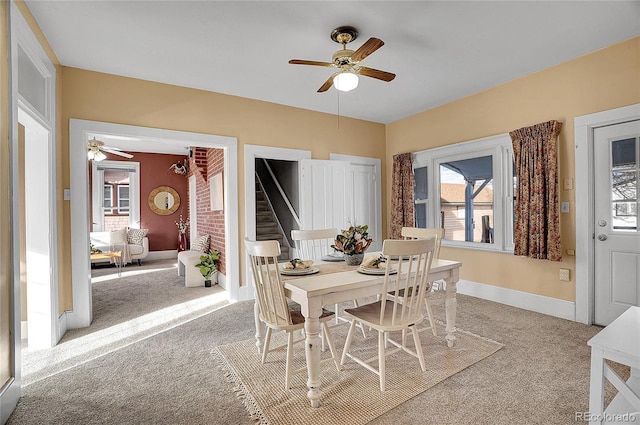 dining room featuring baseboards, a ceiling fan, and light colored carpet