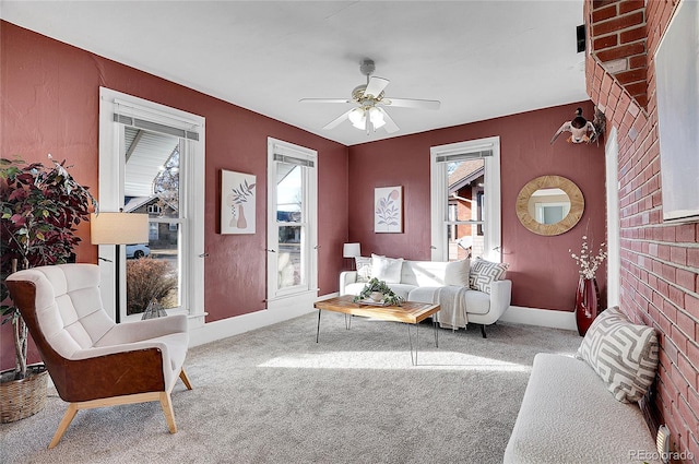 living area with plenty of natural light, carpet flooring, a ceiling fan, and baseboards