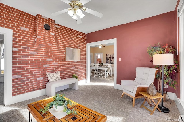 sitting room with a baseboard heating unit, brick wall, carpet, and baseboards