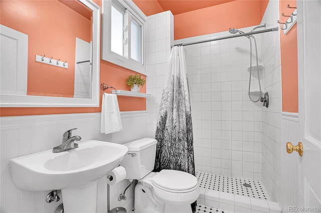 full bathroom with a stall shower, a wainscoted wall, and toilet