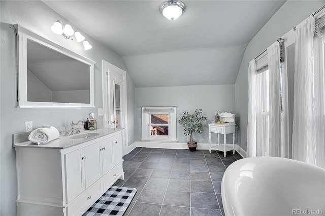 bathroom with a wealth of natural light, vaulted ceiling, vanity, and baseboards