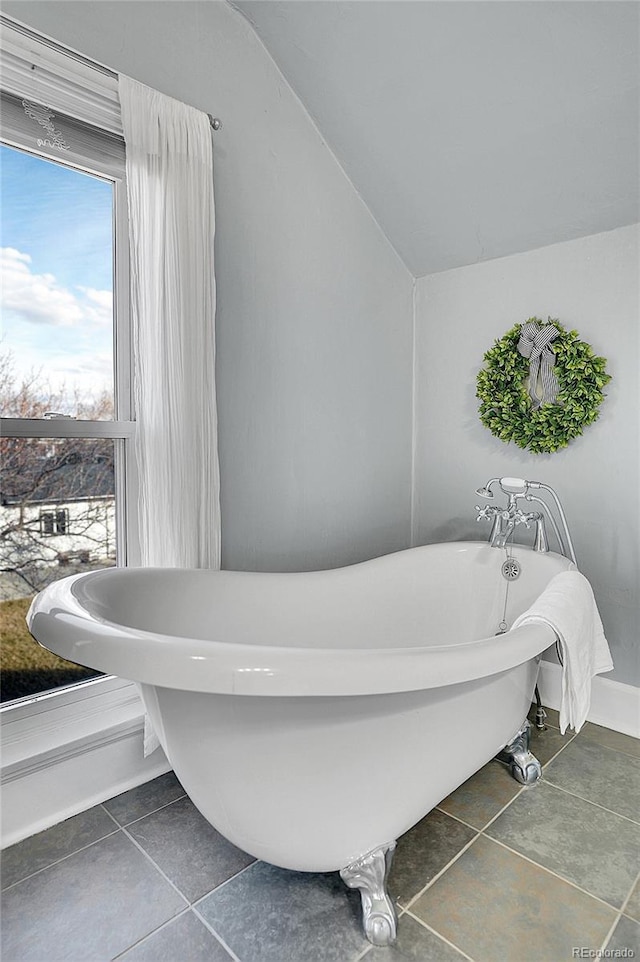 full bath with lofted ceiling, a freestanding tub, and tile patterned floors