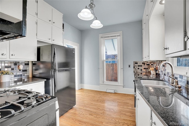 kitchen with a sink, range with gas stovetop, white cabinets, light wood finished floors, and pendant lighting