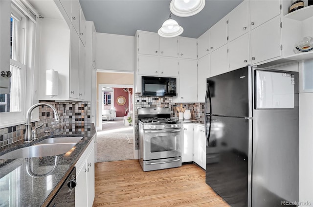 kitchen with light wood finished floors, white cabinets, dark stone countertops, black appliances, and a sink