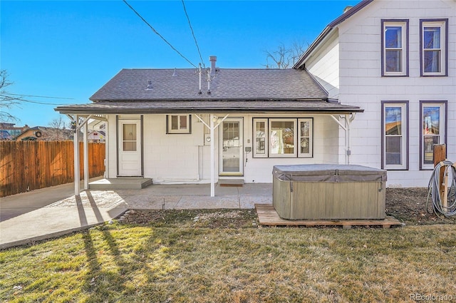 back of house featuring a shingled roof, a patio area, fence, and a hot tub