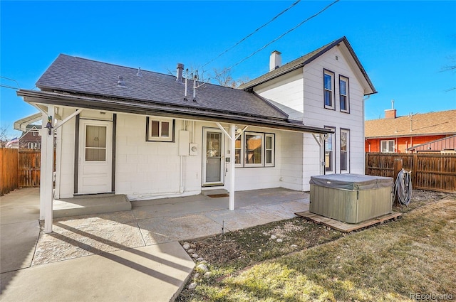 rear view of house with a patio area, a hot tub, a fenced backyard, and roof with shingles