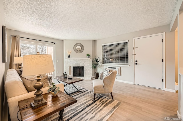 14602 E 2nd Ave Unit 200C, Aurora, CO 80011 - living area with a textured ceiling, light wood-style flooring, a wall unit AC, and a brick fireplace