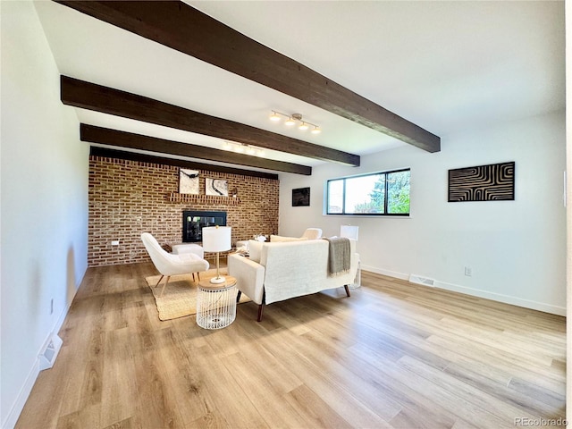 4192 S Vrain St, Denver, CO 80236 - living room with beamed ceiling, light wood finished floors, a brick fireplace, and brick wall