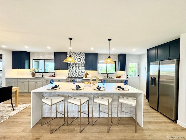 4192 S Vrain St, Denver, CO 80236 - kitchen with stainless steel fridge, tasteful backsplash, light countertops, a kitchen bar, and a spacious island