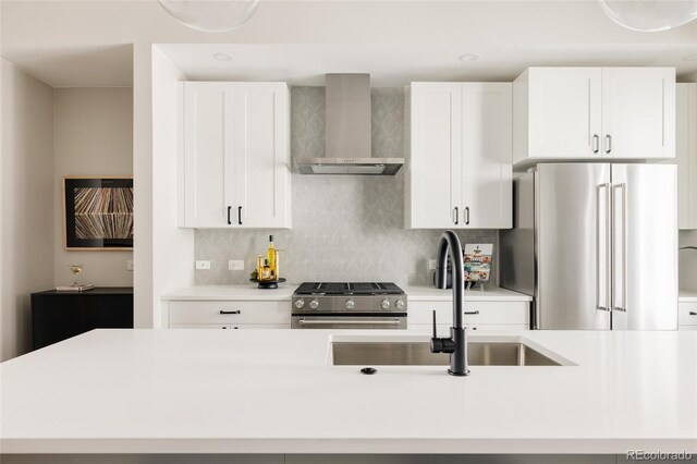 kitchen featuring wall chimney exhaust hood, stainless steel appliances, a sink, light countertops, and tasteful backsplash