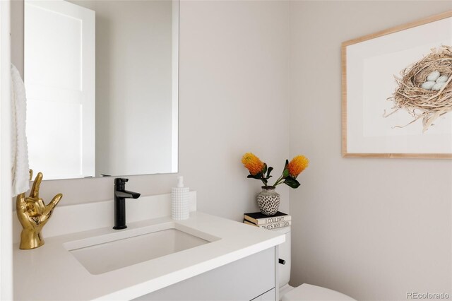 half bathroom featuring vanity and toilet