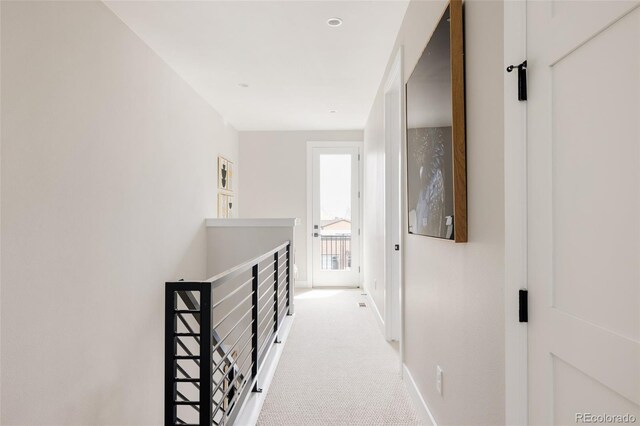 corridor with an upstairs landing, baseboards, and carpet flooring