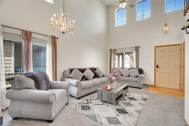 living room featuring light carpet, a high ceiling, and ceiling fan with notable chandelier