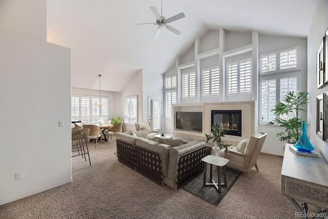 living room with ceiling fan, carpet, a high ceiling, and a tiled fireplace