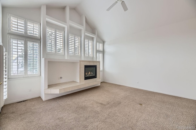 unfurnished living room featuring carpet floors, a tile fireplace, lofted ceiling, and ceiling fan