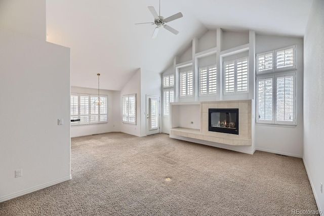 unfurnished living room with a tile fireplace, carpet flooring, high vaulted ceiling, and ceiling fan