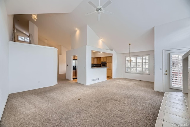 unfurnished living room featuring high vaulted ceiling, light carpet, and ceiling fan with notable chandelier