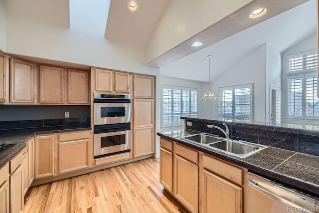 kitchen with appliances with stainless steel finishes, lofted ceiling, sink, pendant lighting, and light brown cabinets